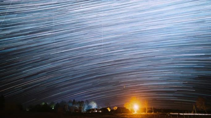 4k延时夜星空村庄上方。乡村景观的天空背景。流星穿越深蓝色的天空。惊人的不寻常的星星效果。明亮的蓝色