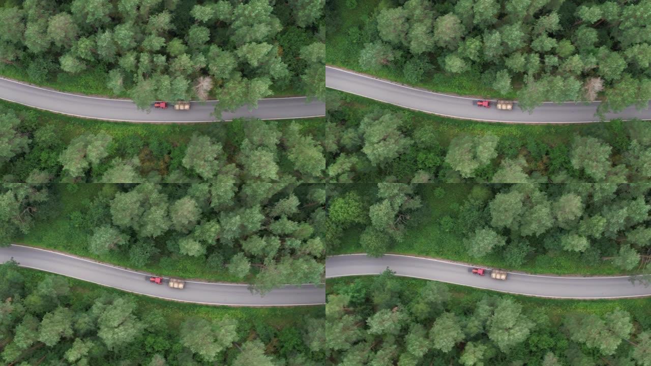 红色拖拉机携带波兰的干草林路。农用拖拉机、农用机械农业自然季节性工程。鸟瞰式农用拖拉机沿着乡村道路驶