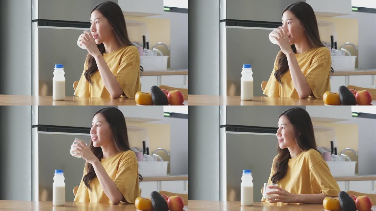 年轻的亚洲妇女在家中厨房喝牛奶，健康的生活方式