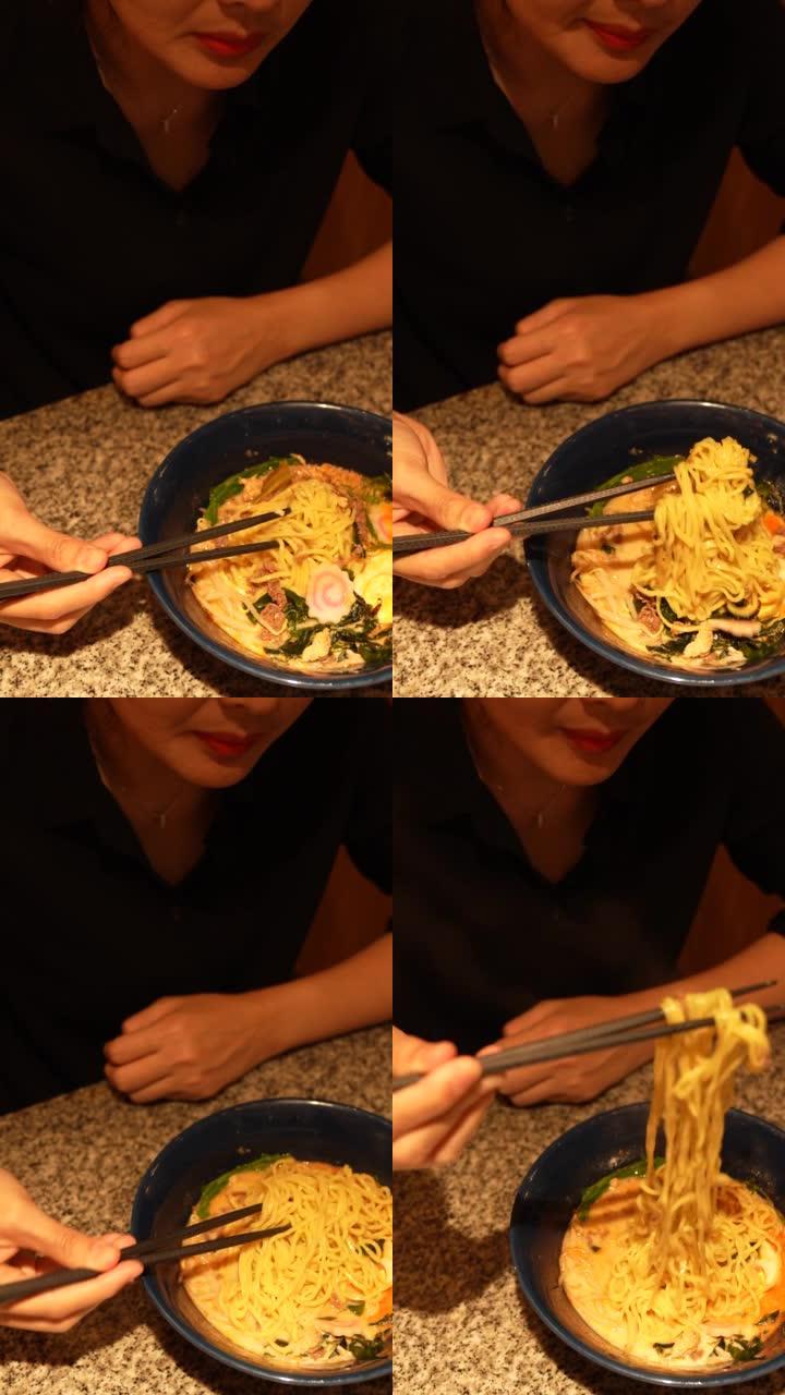 在一家日本餐馆里，女人用筷子吃着一碗新鲜的传统日本拉面。亚洲美食和饮食文化。外出就餐的生活方式-