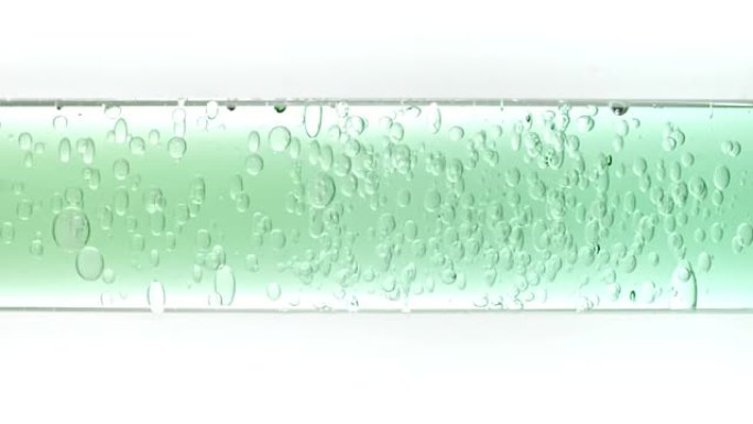 透明化妆品凝胶流体，分子气泡和油在玻璃管中流动，白色背景上有透明液体。宏观拍摄。生产特写。慢动作。
