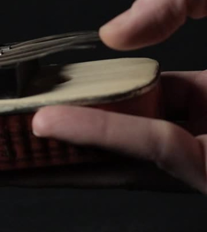 一只手的镜头显示如何在黑暗背景上演奏手工制作的Kalimba乐器