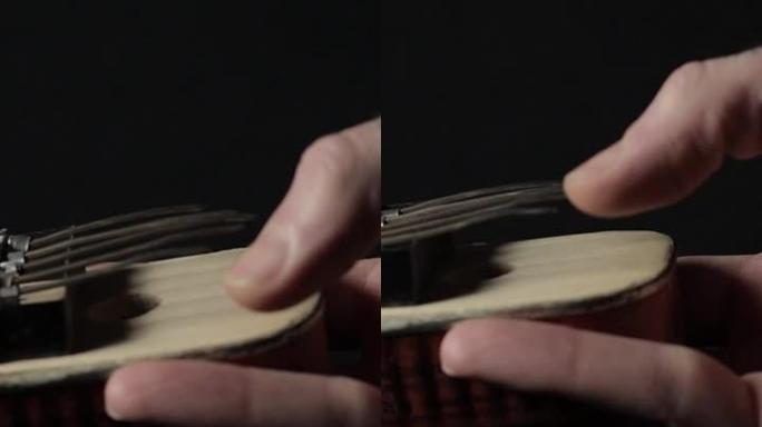 一只手的镜头显示如何在黑暗背景上演奏手工制作的Kalimba乐器