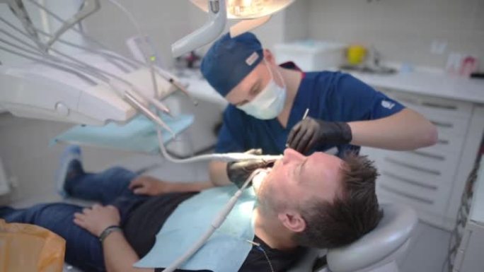 医疗中心的牙医和病人。医生使用牙科工具为成熟男人的牙齿进行专业的口腔卫生