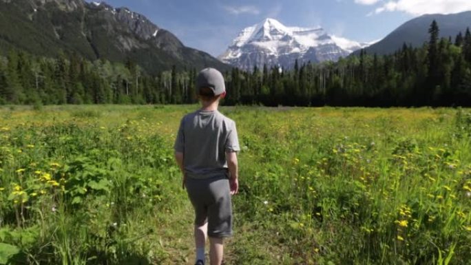 一个小男孩跑向加拿大不列颠哥伦比亚省的罗布森山