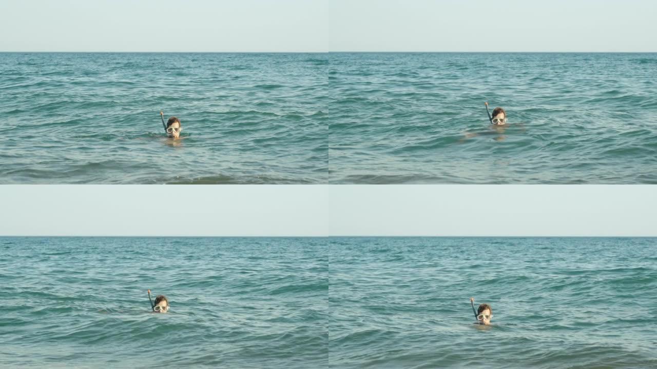 一个戴着潜水面具的男人在海浪上摇摆，只有他的头在表面上可见。看着摄像机。