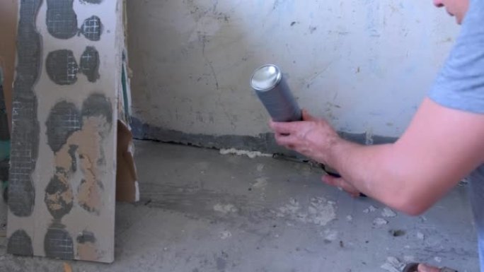 男工在房间里用安装泡沫填充墙壁和水泥地板之间的裂缝。