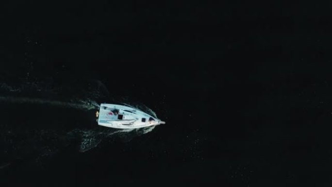 在黑暗的水上航行的游艇的酷炫镜头。游乐游艇的俯视图
