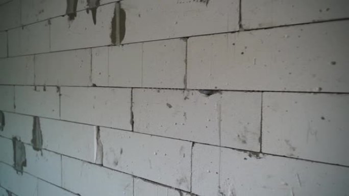 摄像机沿着加气混凝土块的墙壁平滑移动特写。建造过程中房屋的裸露墙壁