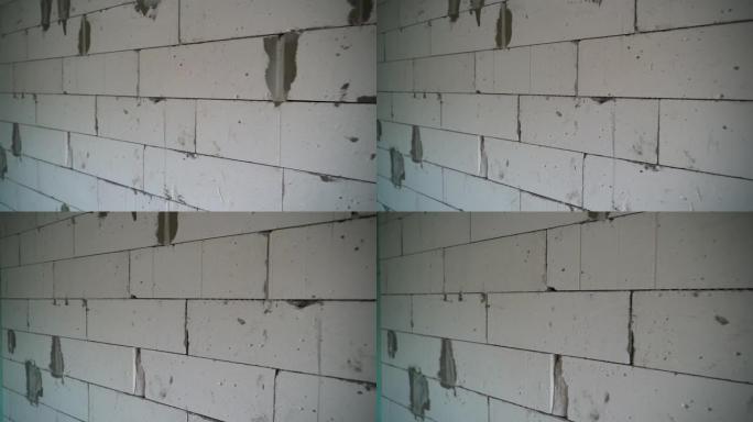 摄像机沿着加气混凝土块的墙壁平滑移动特写。建造过程中房屋的裸露墙壁