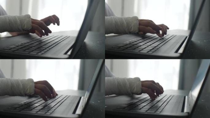无法辨认的小女孩的特写镜头被白色石膏绷带包裹着，用白色石膏绷带打字在坐在桌子上的笔记本电脑上学习。