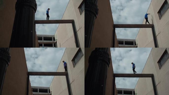 一名年轻男性在建筑物之间的杆子上做跑酷的低角度镜头