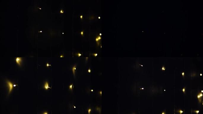 花环的灯点亮并在墙上熄灭。抽象模糊的灯光在黑色背景上闪闪发光。圣诞节或新年假期概念。