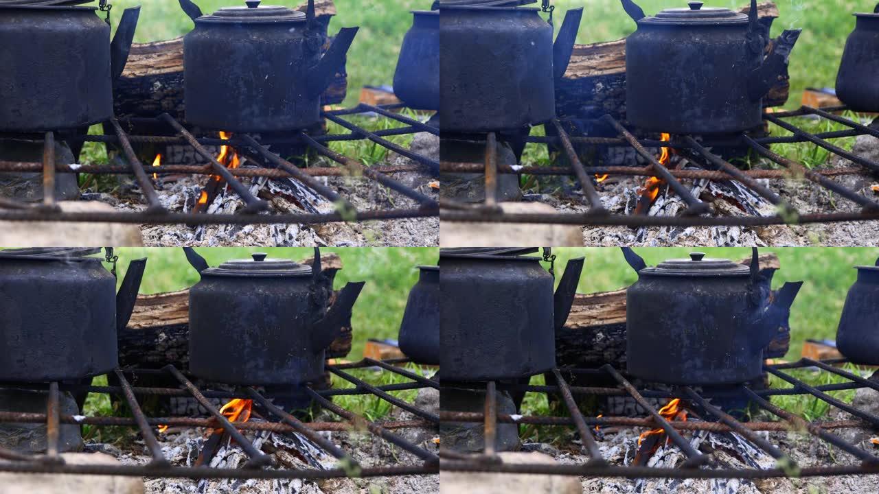 在篝火上的铁炉上是用于在野外条件下沸腾poda的黑色水壶