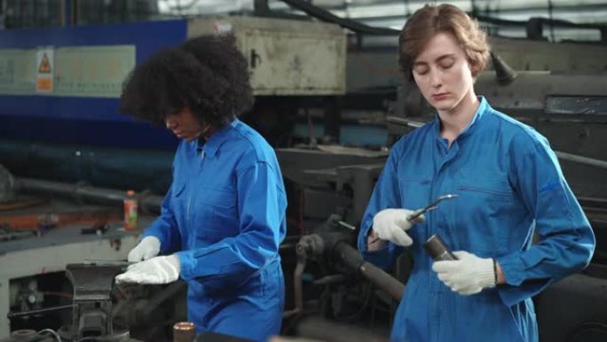 Mix race穿着安全服的年轻女机械工程师正在共同检查和评估金属工厂生产线中数控机床生产的金属零件