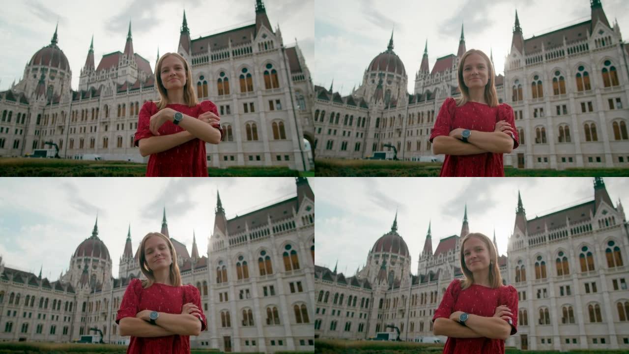 布达佩斯议会大厦附近双臂交叉的快乐年轻女子的画像