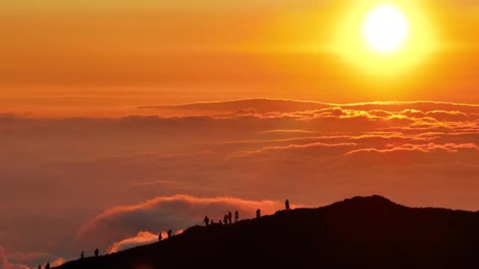 戏剧性的日落期间游客在山顶上的鸟瞰图
