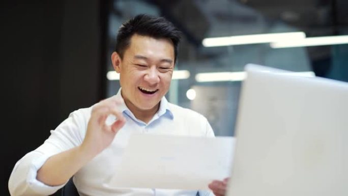 肖像快乐的亚洲男人商业男人雇员阅读文件报告文件项目信息信件银行融资通知喜悦感到幸福庆祝胜利