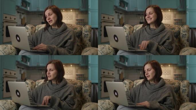 女性在家用笔记本电脑上网聊天。30多岁的女人坐在沙发上进行视频通话。