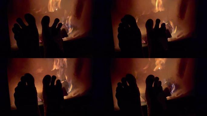4k人坐在壁炉旁伸展双腿，摆动脚手指，享受火的温暖。家居甜蜜家居和节能理念。
