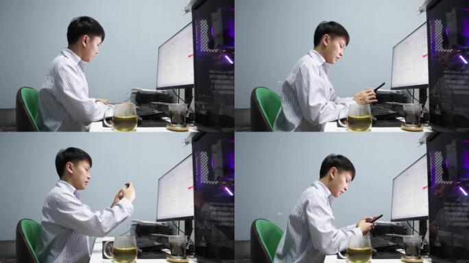 晚上，一名亚裔男子在电脑前拍照发送信息，报告工作进展 -- 年轻人的生活方式