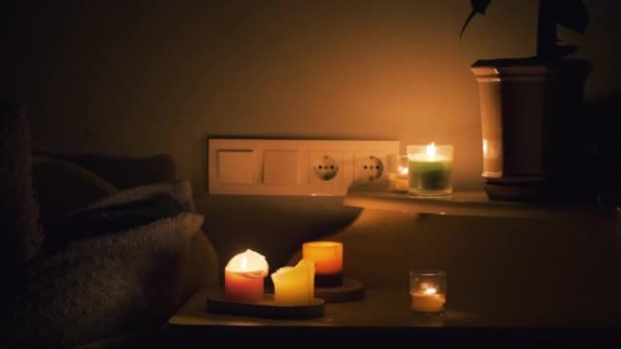 黑暗房间里的蜡烛。在桌子上燃烧蜡烛，在背景上燃烧插座。房子里没有电。城市停电。停电，能源危机概念