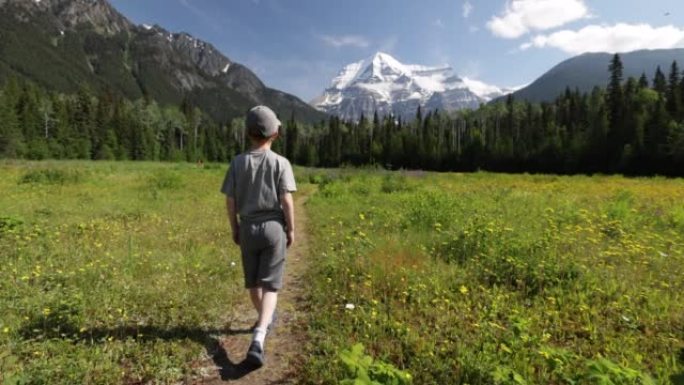 一个小男孩跑向加拿大不列颠哥伦比亚省的罗布森山