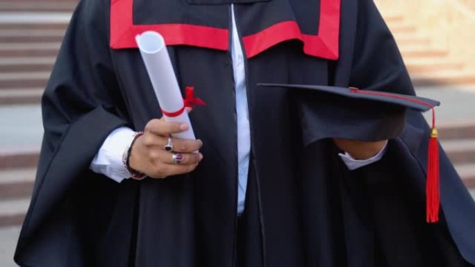 穿着毕业礼服的印度男子的特写拿着文凭和帽子