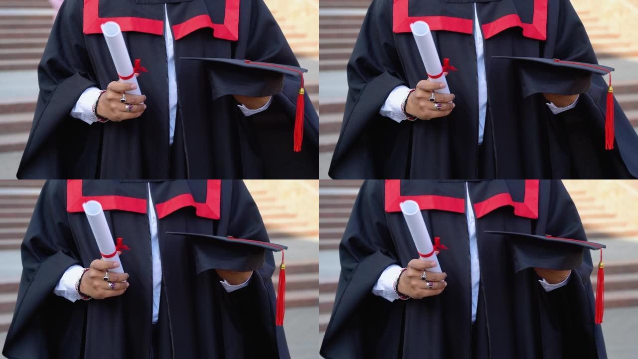 穿着毕业礼服的印度男子的特写拿着文凭和帽子