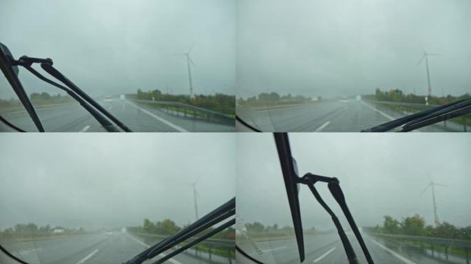 在雨中，在阴沉的天气里，在高速公路上行驶。雨刮器擦拭汽车雨水浸湿的挡风玻璃。
