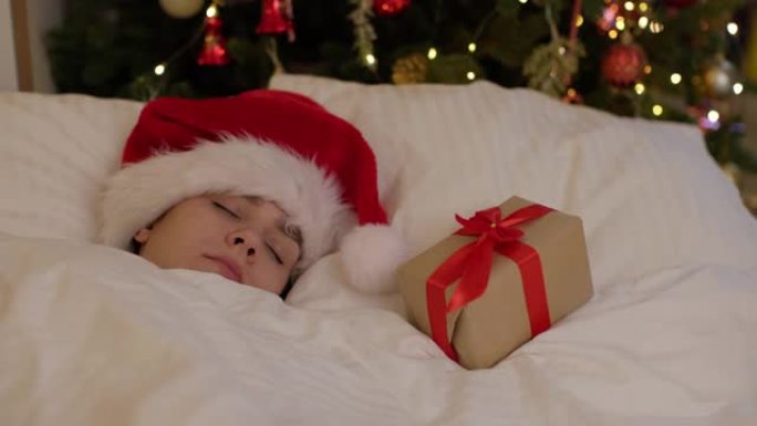 漂亮的年轻女子圣诞老人帽子卧室靠近装饰的圣诞灯树