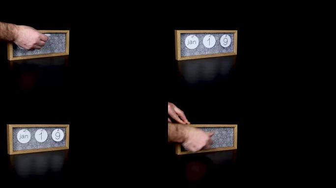一个木制日历块，用男人的手1月19日和取下带有日期和月份的金属盘，以4k质量拍摄