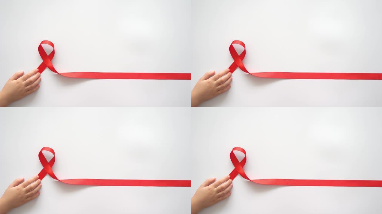 白色背景上的儿童手中的援助红丝带，象征着与艾滋病毒，艾滋病和癌症作斗争。帮助有需要的人的概念。慈善，
