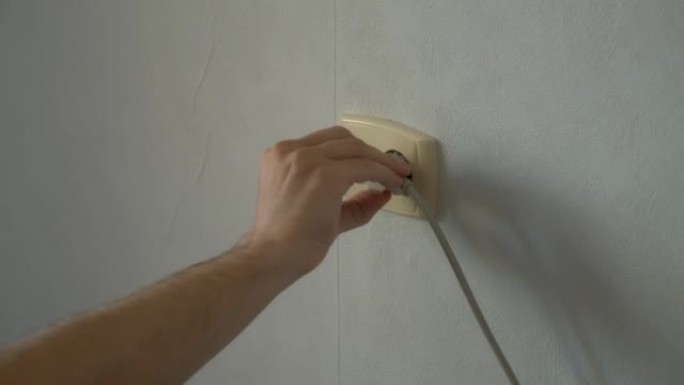 人的手将电器的插头叉关闭到插座中。
