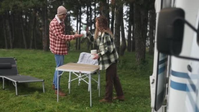 两个露营者在露营者面前摆了一张折叠桌，喝咖啡