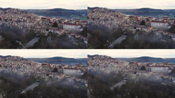 4k，Veliko Tarnovo的鸟瞰图。秋天和雾低垂。低头看着云。房屋和通往小镇的道路