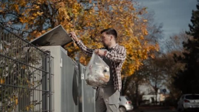 一名男子将一袋垃圾带到垃圾桶，然后在德国将其丢弃。倒垃圾。男性丢弃了一个装有生物食物垃圾的垃圾袋。房
