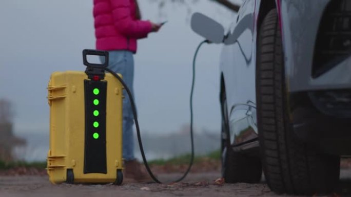 女孩使用家庭发明的便携式电动汽车充电器，闪烁指示其工作