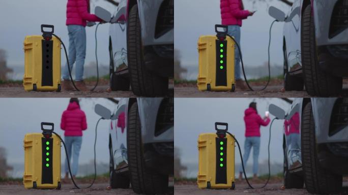 女孩使用家庭发明的便携式电动汽车充电器，闪烁指示其工作
