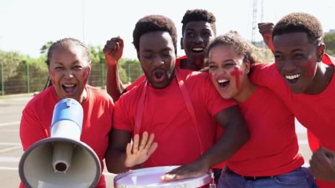 多代非洲足球支持者球迷穿着红色t恤在体育场观看足球比赛