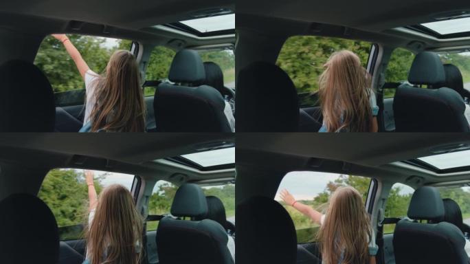 旅行概念，相当快乐的少女把头和手伸出车窗，在旅行中欣赏风景