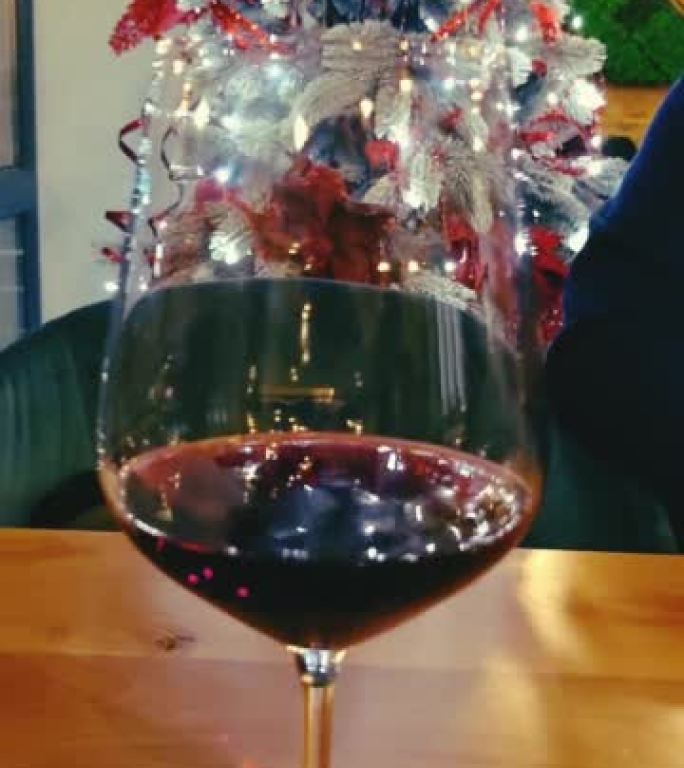 圣诞树背景上的一杯红酒