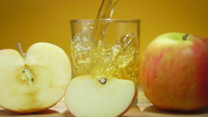 苹果汁倒在黄色背景上的玻璃杯中