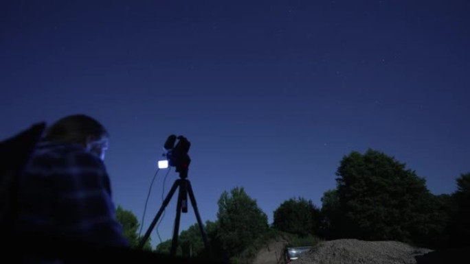 一名男子在夜间用相机拍摄星空的延时镜头