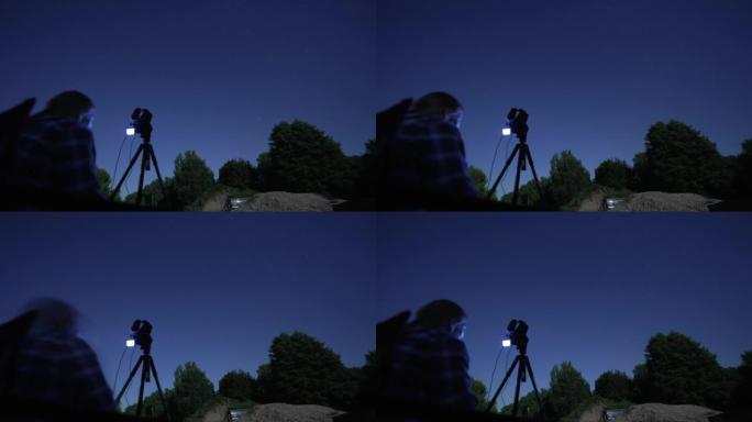 一名男子在夜间用相机拍摄星空的延时镜头