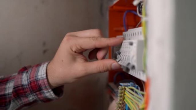 手动切换房屋电气屏蔽层中的电力自动开关。工程师或电工的手检查电气系统。带断路器的电力控制面板。