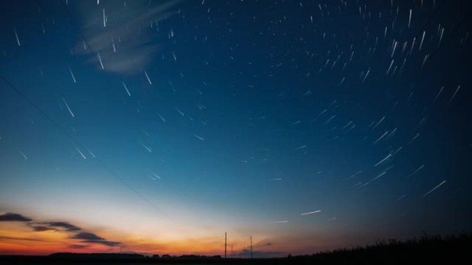 4k延时夜星空。黎明来了。天空中惊人的星星效果。黎明天空。柔和的蓝橙粉色。电力线上方的星星踪迹。夜空