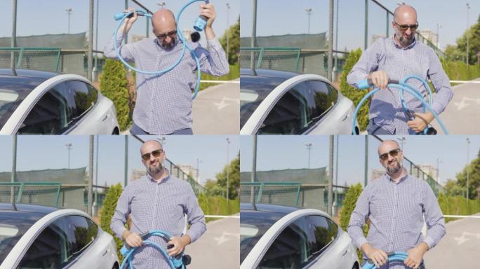 留着胡须和太阳镜的大胆男人对电动汽车的充电电缆有问题。