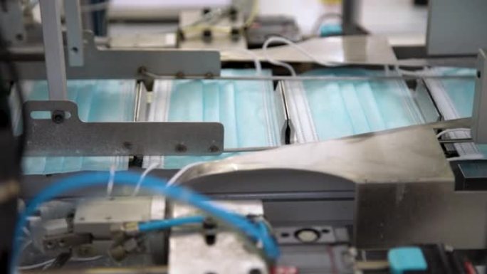 工厂生产医用口罩的特写过程。大量制造呼吸医用口罩的自动化机械。