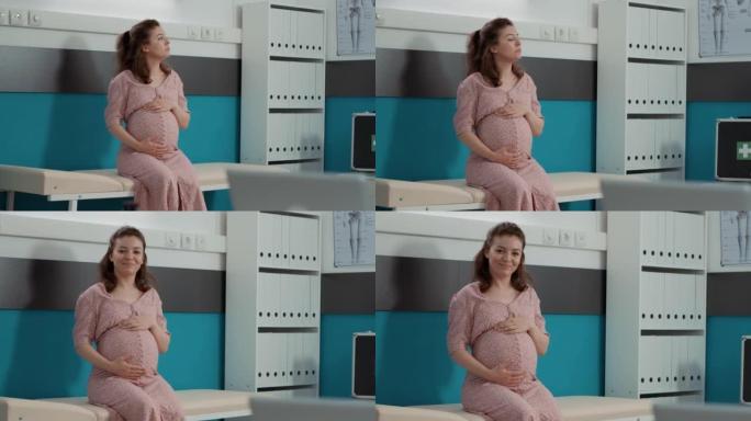 肖像的未来母亲与婴儿隆起坐在橱柜床上